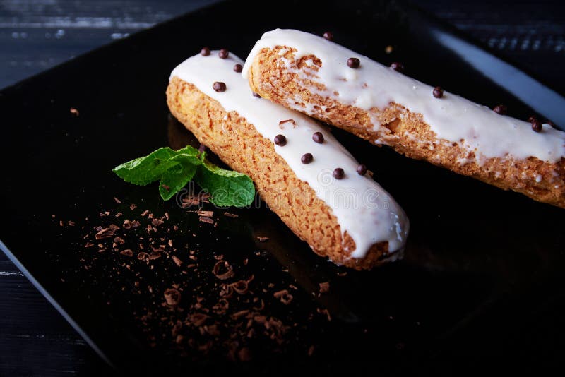 Two Exquisite Cream Dessert Eclair with Fresh Mint Leaves Stock Photo