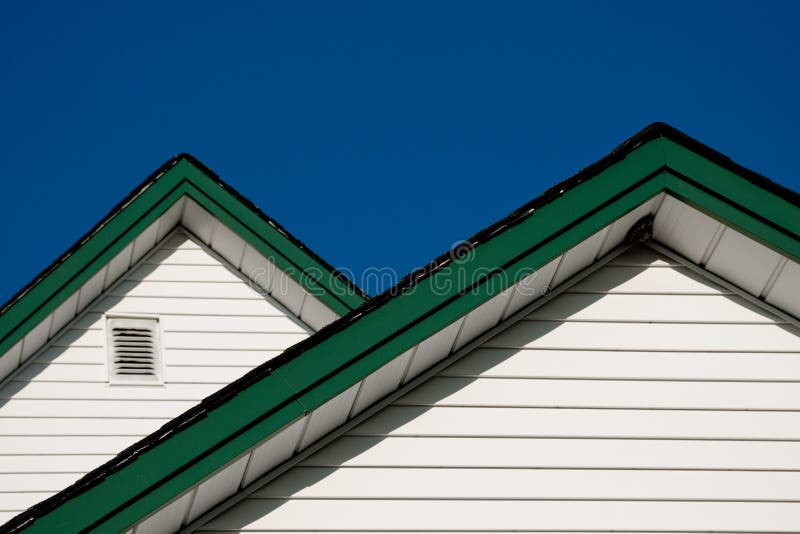 Two farmhouse roof peaks against a blue sky