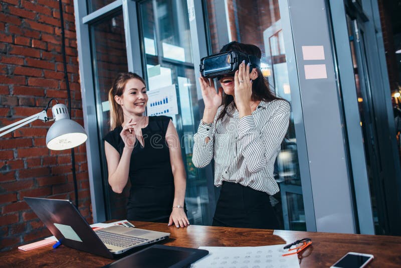 Two female application developers testing a new app designed for VR headset standing in modern office royalty free stock photo