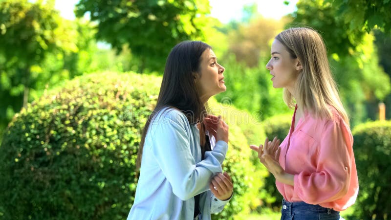 Two female friends arguing outdoors, relations confrontation, communication