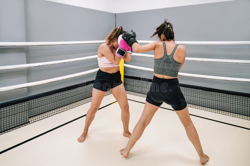 Two Female Kickboxers Practicing Punching Each Other in a Ring Stock