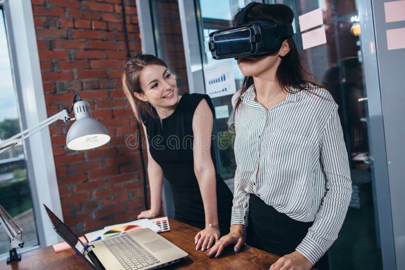 Two female students playing a 3d game in VR glasses having a break after a lesson in the classroom royalty free stock image
