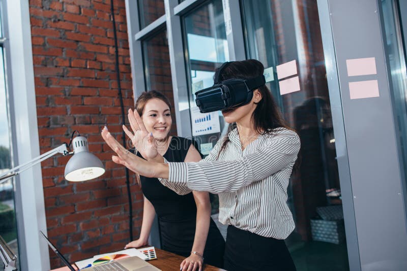 Two female students playing a 3d game in VR glasses having a break after a lesson in the classroom stock images