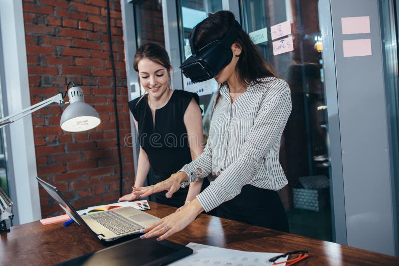 Two female students playing a 3d game in VR glasses having a break after a lesson in the classroom stock image