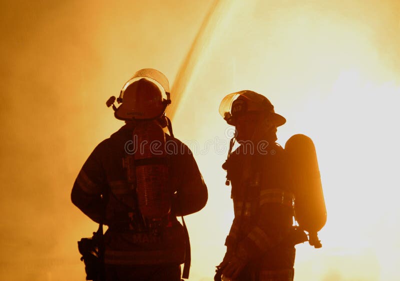 Due vigili del fuoco si stagliano da un furioso inferno.