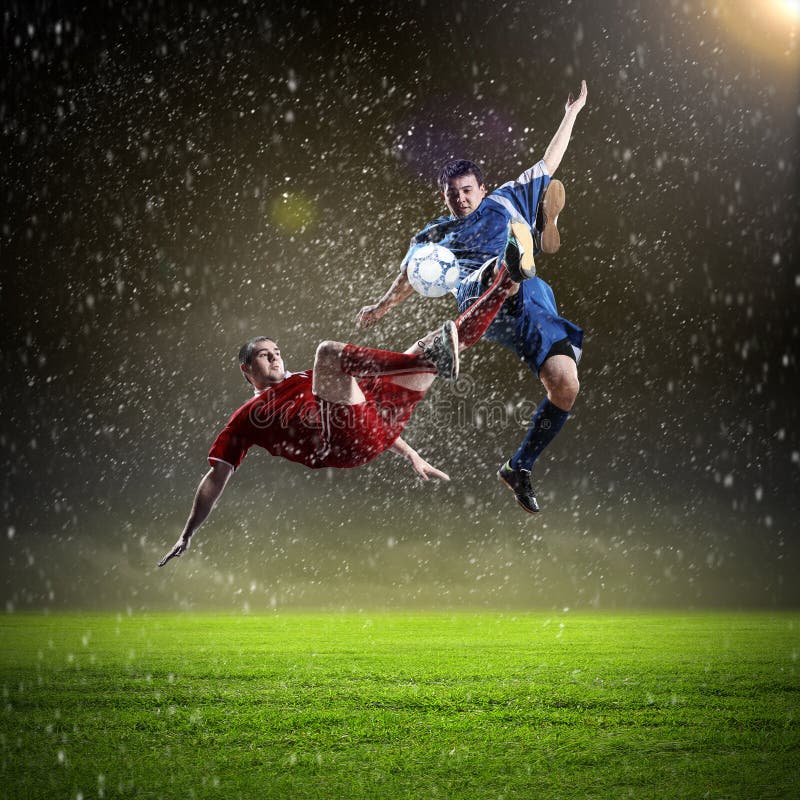 Dvě fotbal hráči v skok na udeřit koule na stadion.