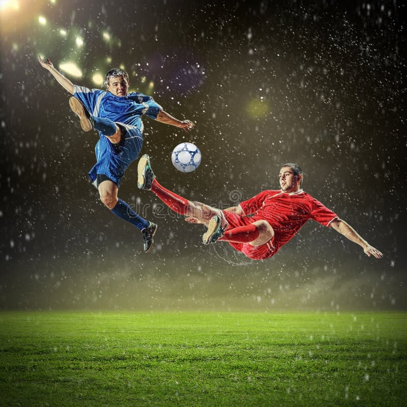 Dvě fotbal hráči v skok na udeřit koule na stadion.