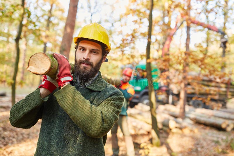 Two forest workers carry a tree trunk