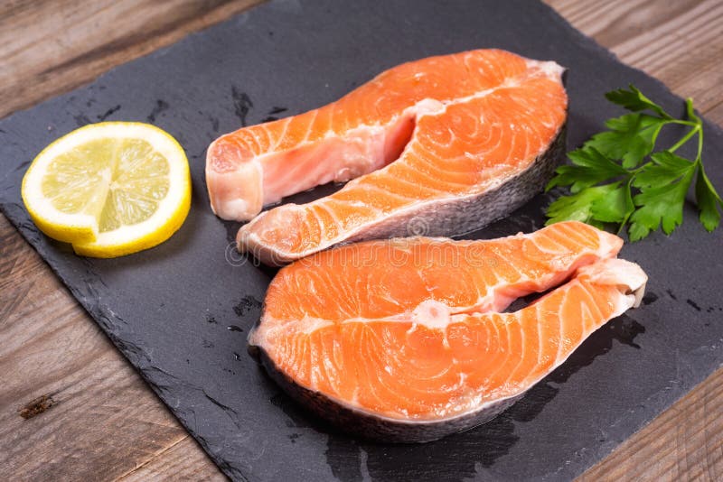 Two fresh raw salmon steaks with lemon and parsley on the rustic table stock photos Two fresh raw salmon steaks with lemon and parsley on the rustic table stock photos