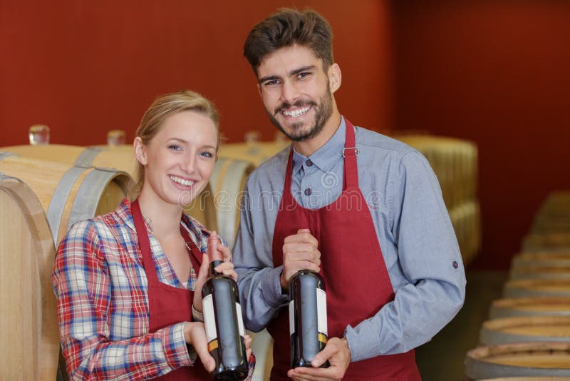 Two Friendly Smiling Winemakers in Uniform Examining Bottle Wine Stock