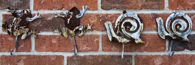 Weathered Frog and Snail Hooks Attached To a Brick Wall Stock