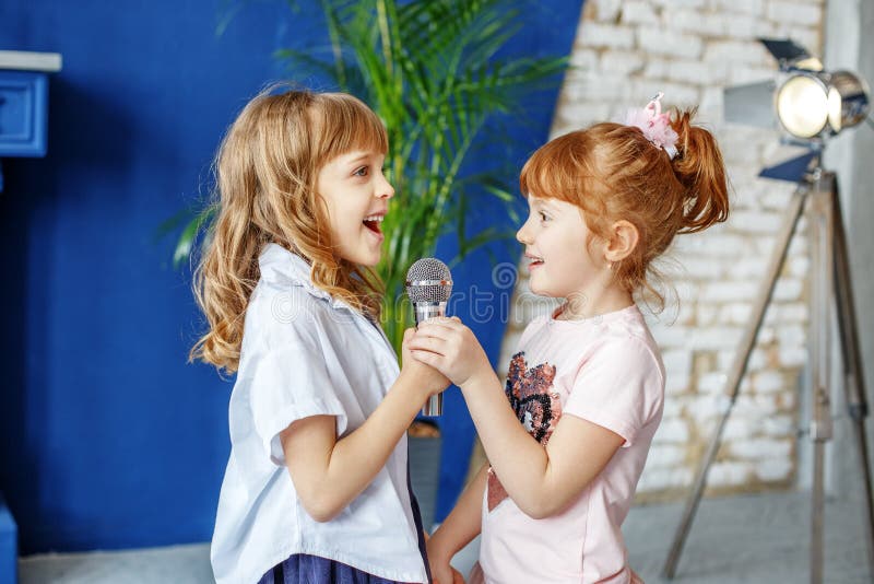 Two funny kids sing a song in karaoke. The concept is childhood, lifestyle, music, singing, friendship.