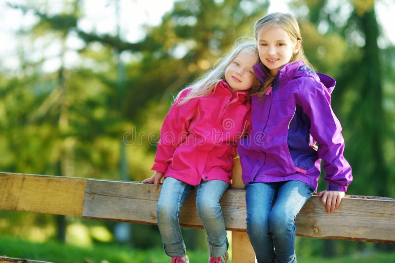 Two funny little sisters having fun during forest hike on beautiful autumn day in Italian Alps