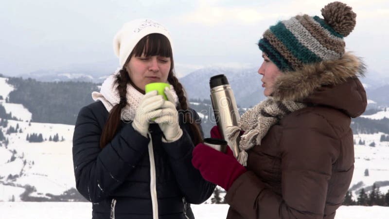 Two girlfriends have tea in mountains