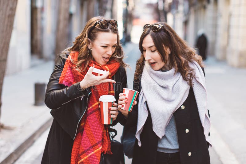 Two girlfriends looking into a coffee cup with shocked faces - customer bad experience concept