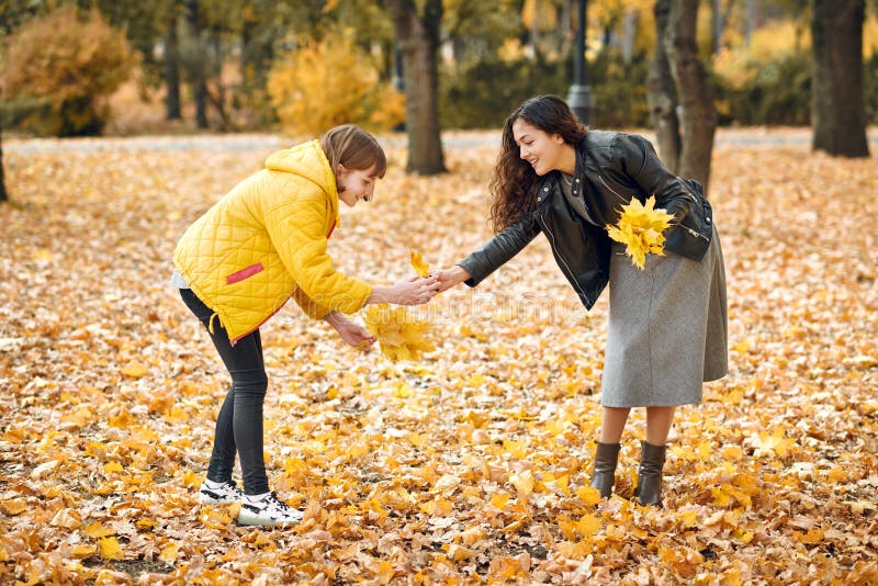Two Girls Are In Autumn City Park They Pick Leaves Stock Image Im