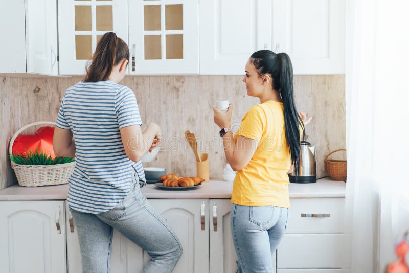 Two Girls Drink Coffee with Croissants in the Kitchen Stock Image