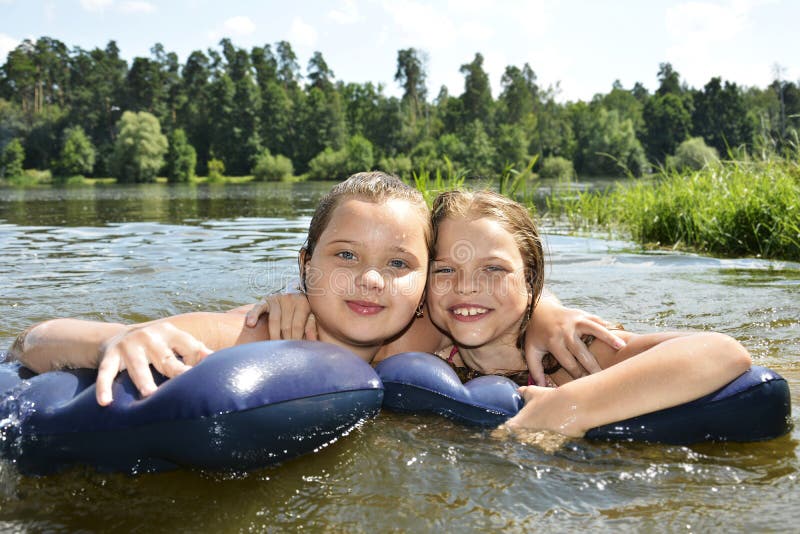 Two girls girlfriends on summer lake swimming in the lake and sm