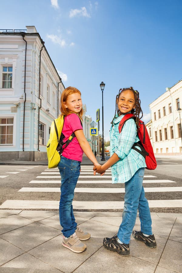 Two girls holding hands and standing near road