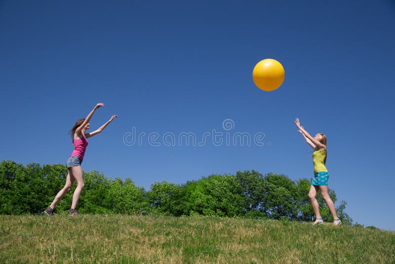 Two girls play with yellow ball