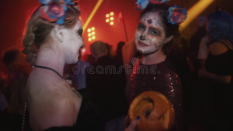 Two girls with santa muerte face paint dance at night club halloween party