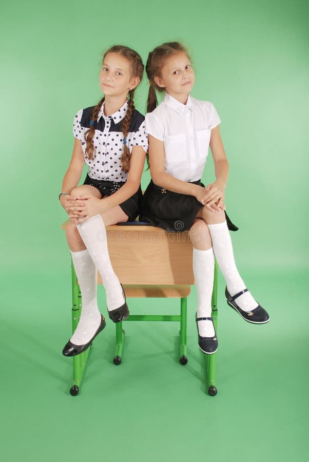 Two girls in a school uniform sitting on desk