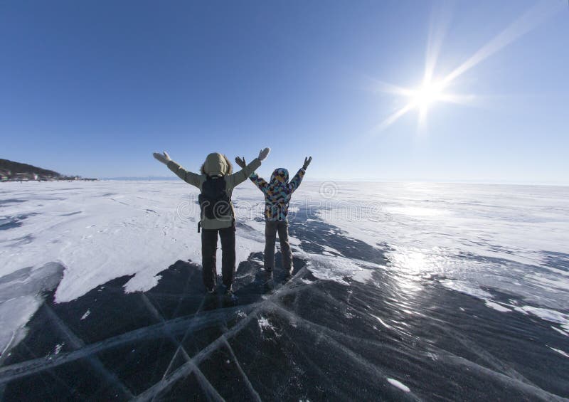 Two girls standing on the ice of frozen lake with his hands up. Baikal siberia russia. People embracing nature with open royalty free stock images Two girls standing on the ice of frozen lake with his hands up. Baikal siberia russia. People embracing nature with open royalty free stock images