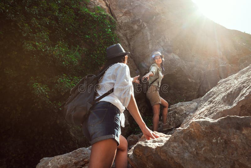 Two girls of a tourist`s girlfriend climb the mountains, help each other, reach out a helping hand.