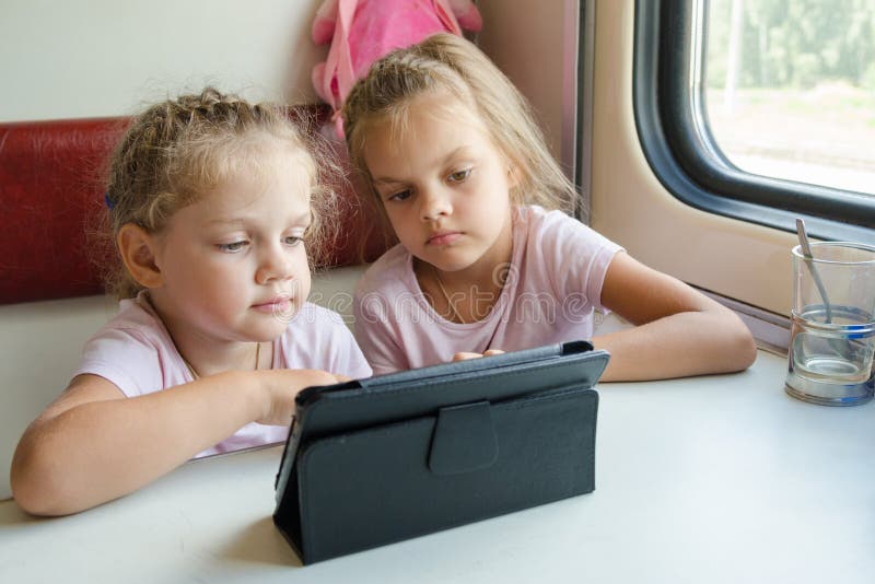 Two girls on a train watching a cartoon in the plate