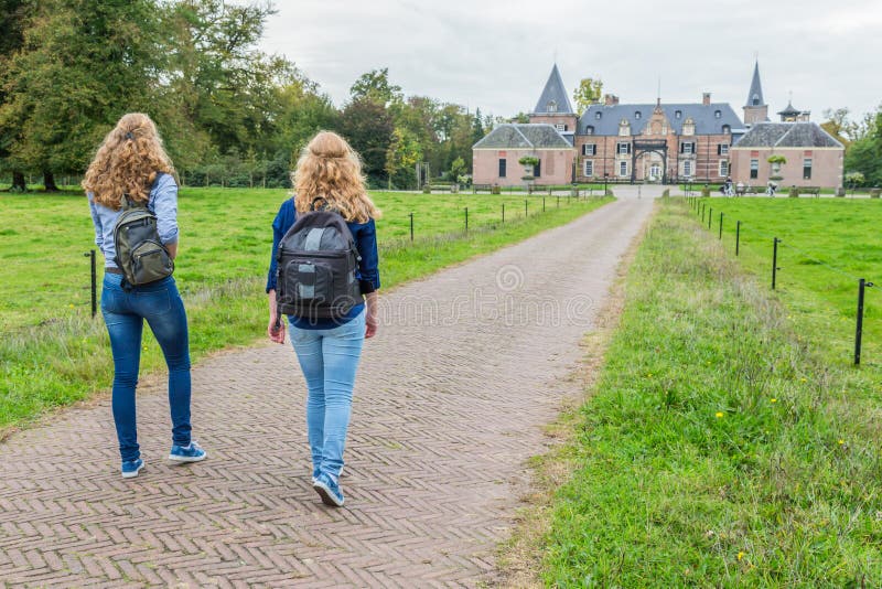 Two girls walking on road leading to castle