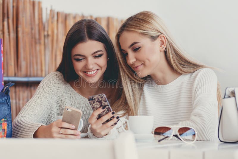 Two girls are watching photos on smartphone