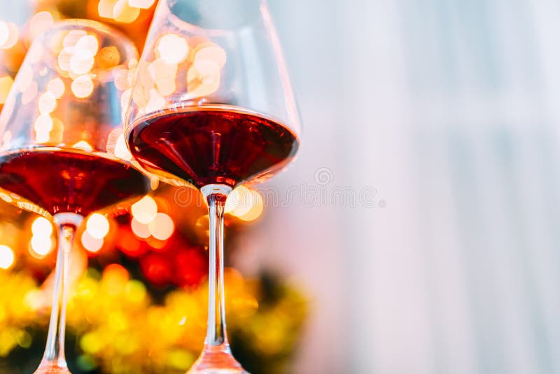 Two glass of red wine in front of christmas tree lights bokeh. New year eve and xmas celebration party