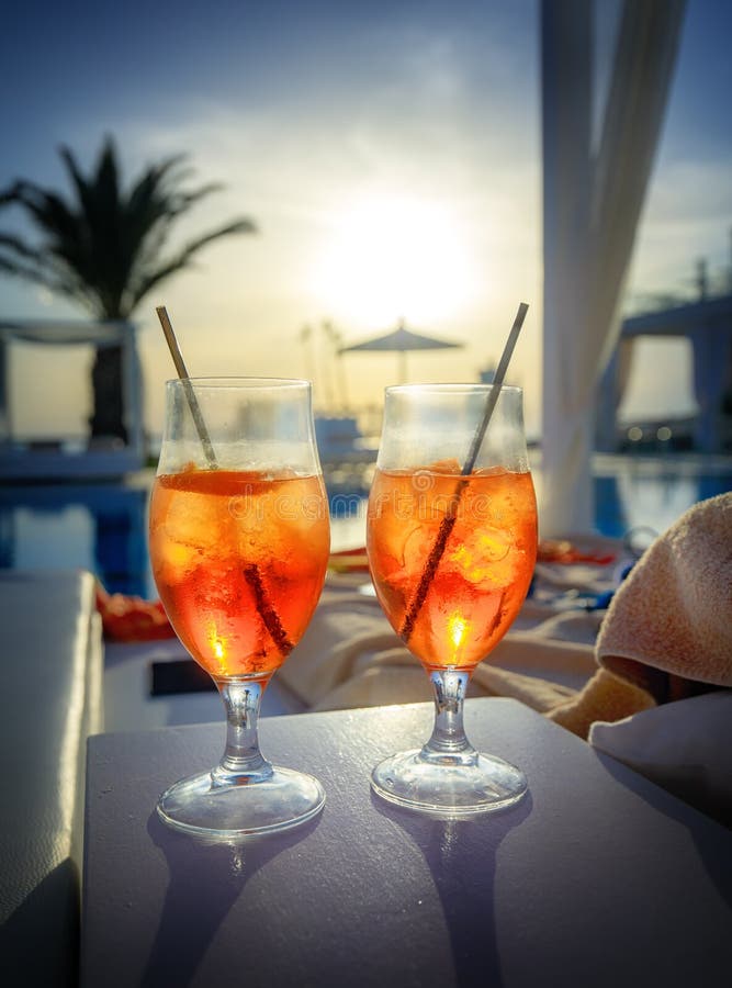 Two glasses with Aperol Spritz aperitif cocktail consisting of prosecco, Aperol and soda water near a swimming pool at sunset royalty free stock photo Two glasses with Aperol Spritz aperitif cocktail consisting of prosecco, Aperol and soda water near a swimming pool at sunset royalty free stock photo