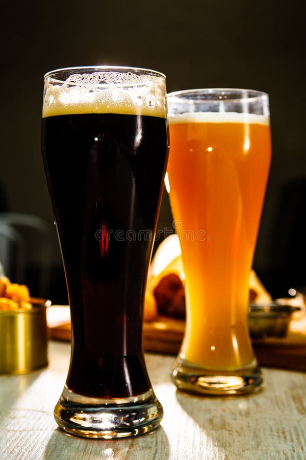 Two glasses of beer standing on the table on a dark background stock images Two glasses of beer standing on the table on a dark background stock images