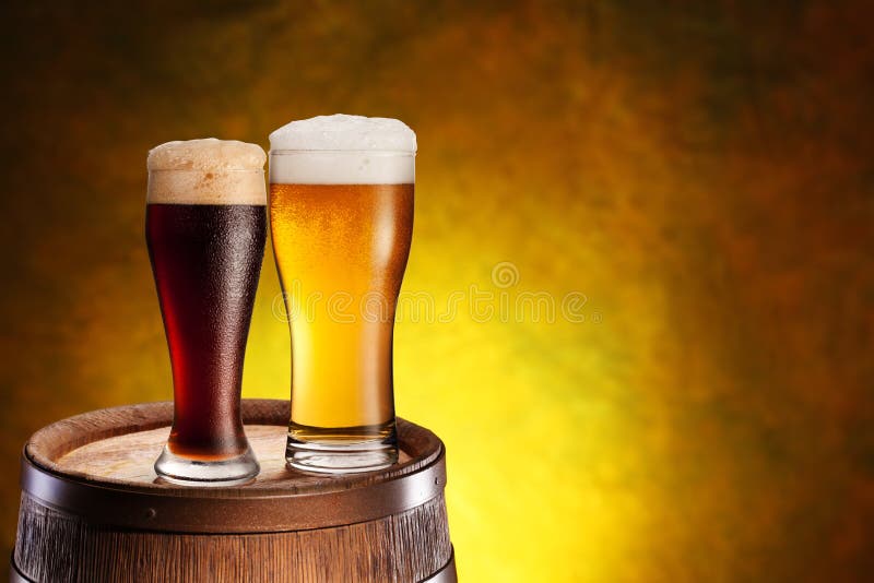 Two glasses of beer on a wooden barrel. royalty free stock image