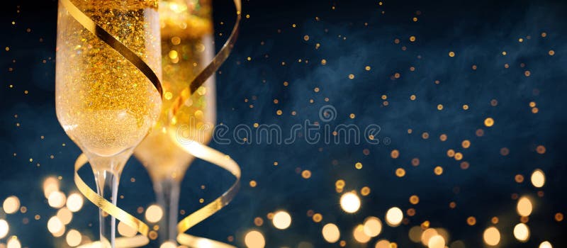 Two glasses of champagne with golden confetti, glitter, serpentine and lights.