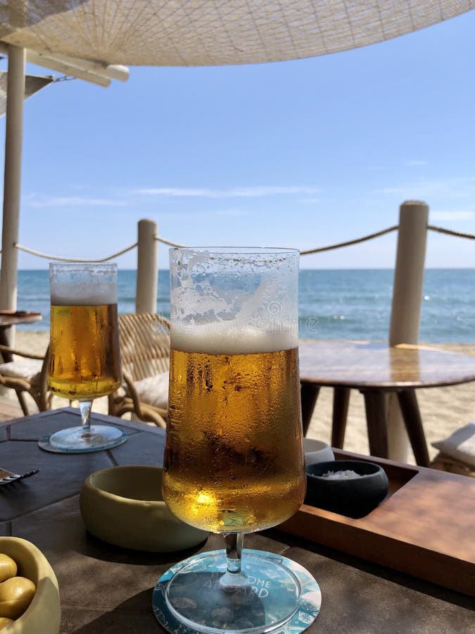 Two glasses of cold beer on a table in a beach bar in front of the Mediterranean Sea, in Malaga, Spain