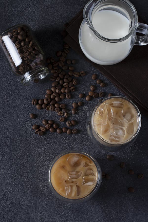 Two Glasses of Cold Coffee with Ice Cubes, Coffee Beans and Jug of Milk