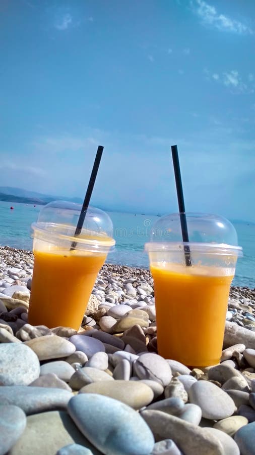 Two glasses of fresh orange juice on pebble beach stock photo Two glasses of fresh orange juice on pebble beach stock photo