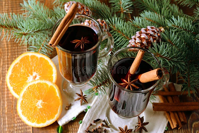 Two glasses of hot mulled wine with,orange and spices on a background of traditional Christmas decorations.