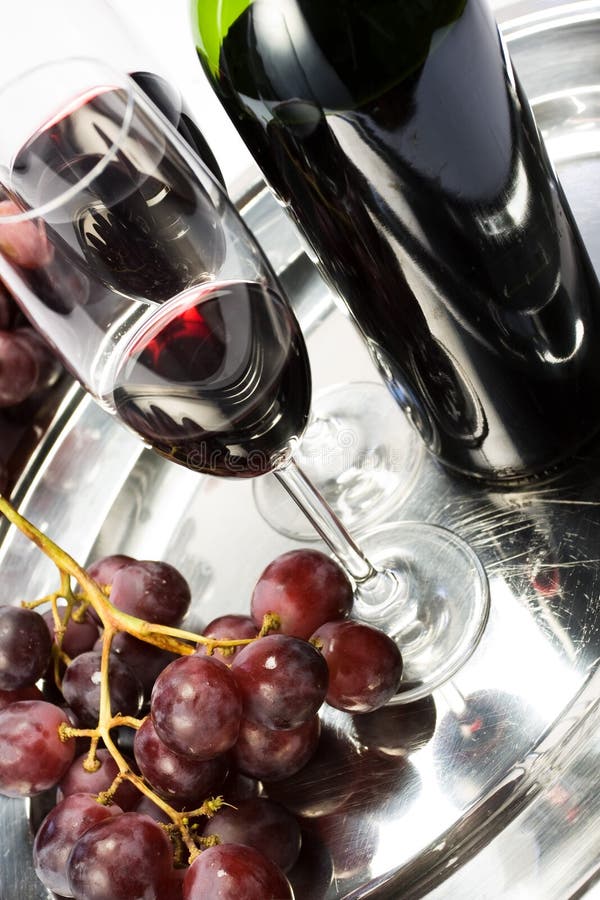 Two glasses of red wine, the bottle and grapes stock photo