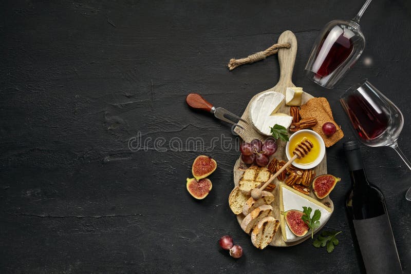 Two glasses of red wine and cheese plate with fruit on the black stone stock photos Two glasses of red wine and cheese plate with fruit on the black stone stock photos