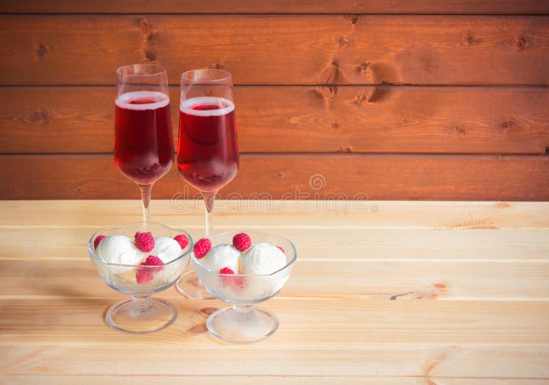 Two glasses of rose champagne and two bowls of sundae ice cream with fresh raspberry