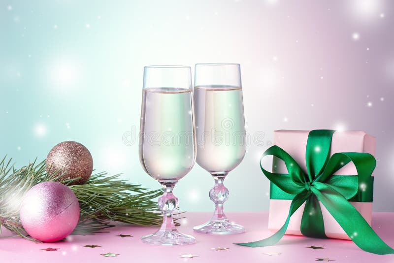 Two glasses of sparkling wine, gift box with bow, decorations. Composition in pink for Christmas, New Year. Still life with drinks and wrapped gift. Two glasses of sparkling wine, gift box with bow, decorations. Composition in pink for Christmas, New Year. Still life with drinks and wrapped gift