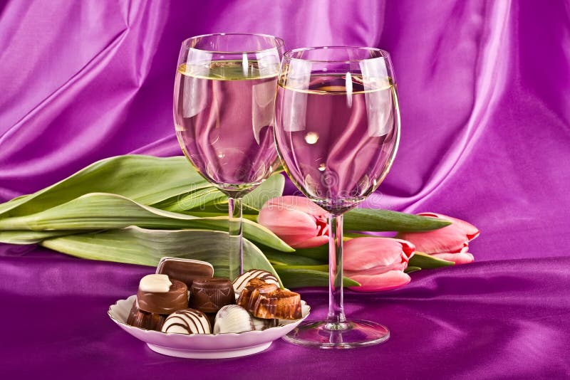 Two glasses of white wine, flowers and sweets