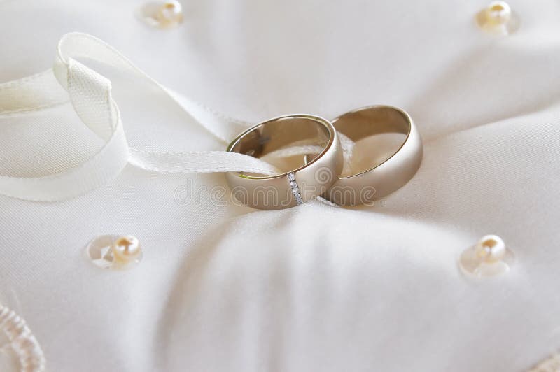 Two gold wedding rings on a pillow