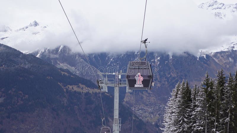 Two gondola lift cabins ascend over a majestic snowy mountain landscape stock footage