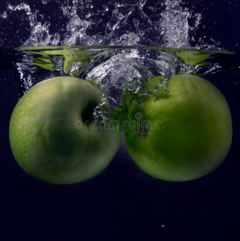 Two Green Apple Under Water with a Trail of Transparent Bubbles. Stock
