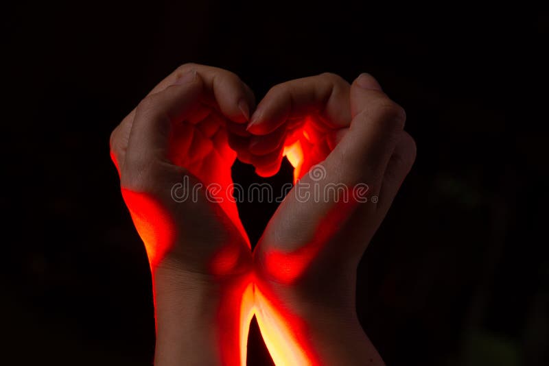 Two hands folded in the shape of a heart, light inside. Clench your hands, symbol of love.