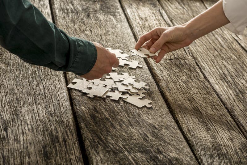 Two hands, male and female, matching two puzzle pieces over a pi